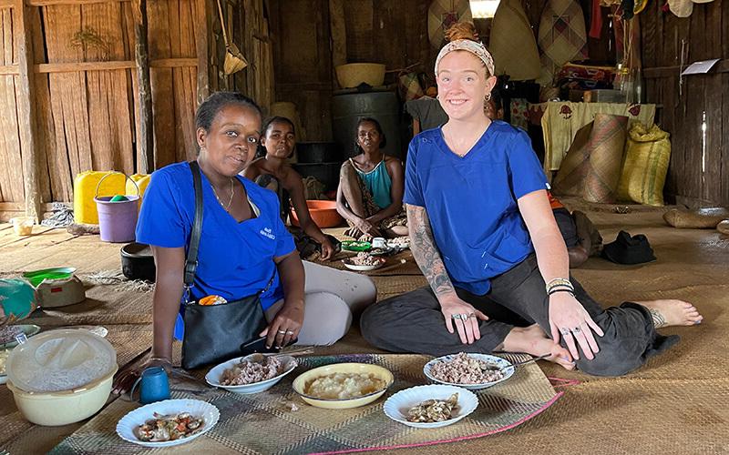 博彩平台推荐 alumna and Peace Corps volunteer Mackenzie Hafer with a family at mealtime in Madagascar