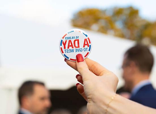 Person holding a sticker that reads "10.19.23: A Day to Give West"